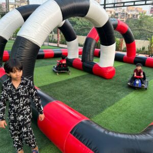 Kids riding mini go-kart cars on inflatable race track at event